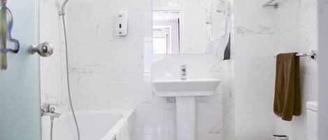 Un baño moderno con una bañera, un lavamanos pedestal y un bidé.
