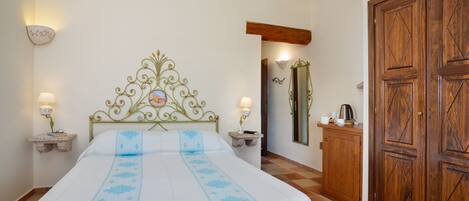 A bedroom with a bed, bedside lamps, a wooden wardrobe, and a mirror on the wall.
