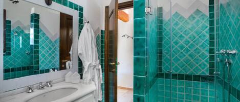Une salle de bain avec un grand miroir, un lavabo et une douche aux carreaux verts.