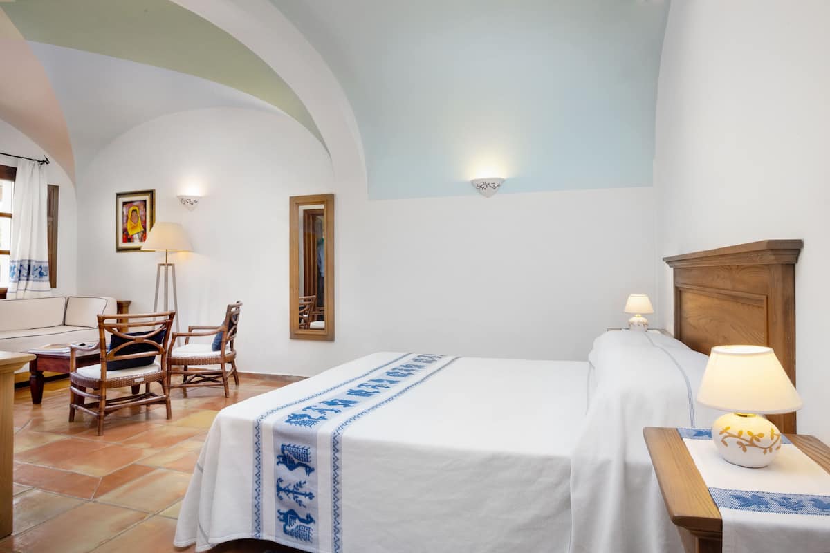 Ein Hotelzimmer mit zwei Betten, einem Holzkopfende, einem Schreibtisch mit Stuhl, einer Lampe und einem Bild an der Wand.