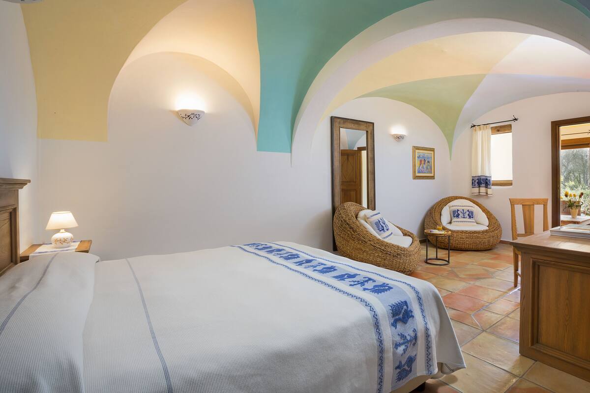Ein Schlafzimmer mit Bett, Stuhl, Tisch und Spiegel.