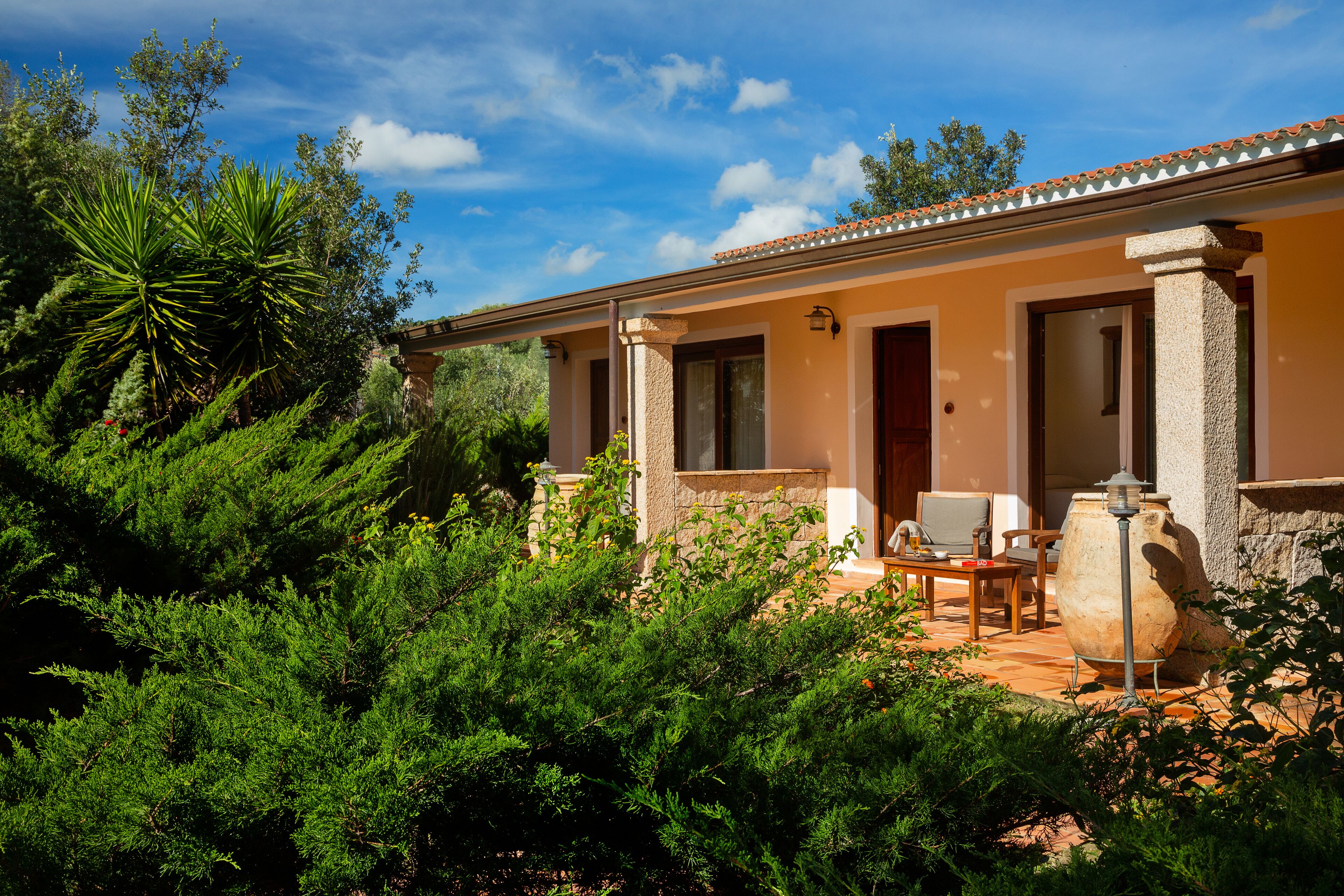 Una casa con un patio, mobiliario exterior y una gran maceta de piedra.