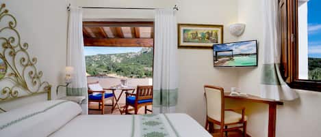 A hotel room with a bed, a desk, a chair, a table, a TV, and a view of the outdoors.