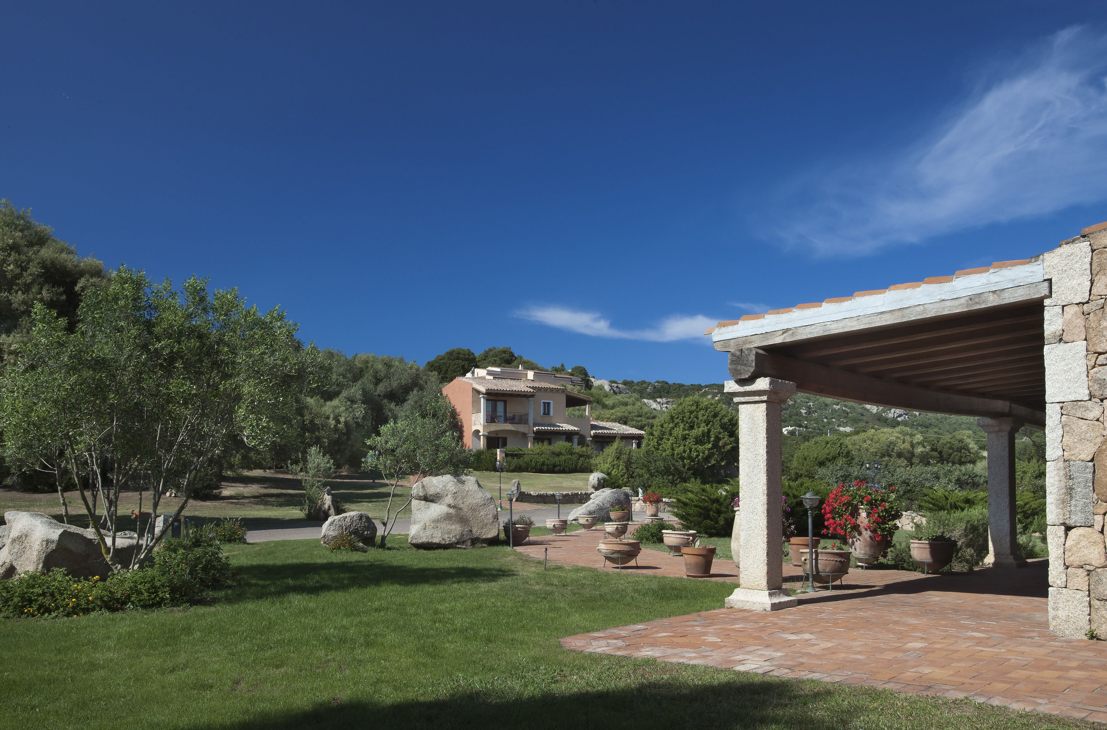 Eine Villa mit einer Steinterrasse, Blumentöpfen und blauem Himmel.