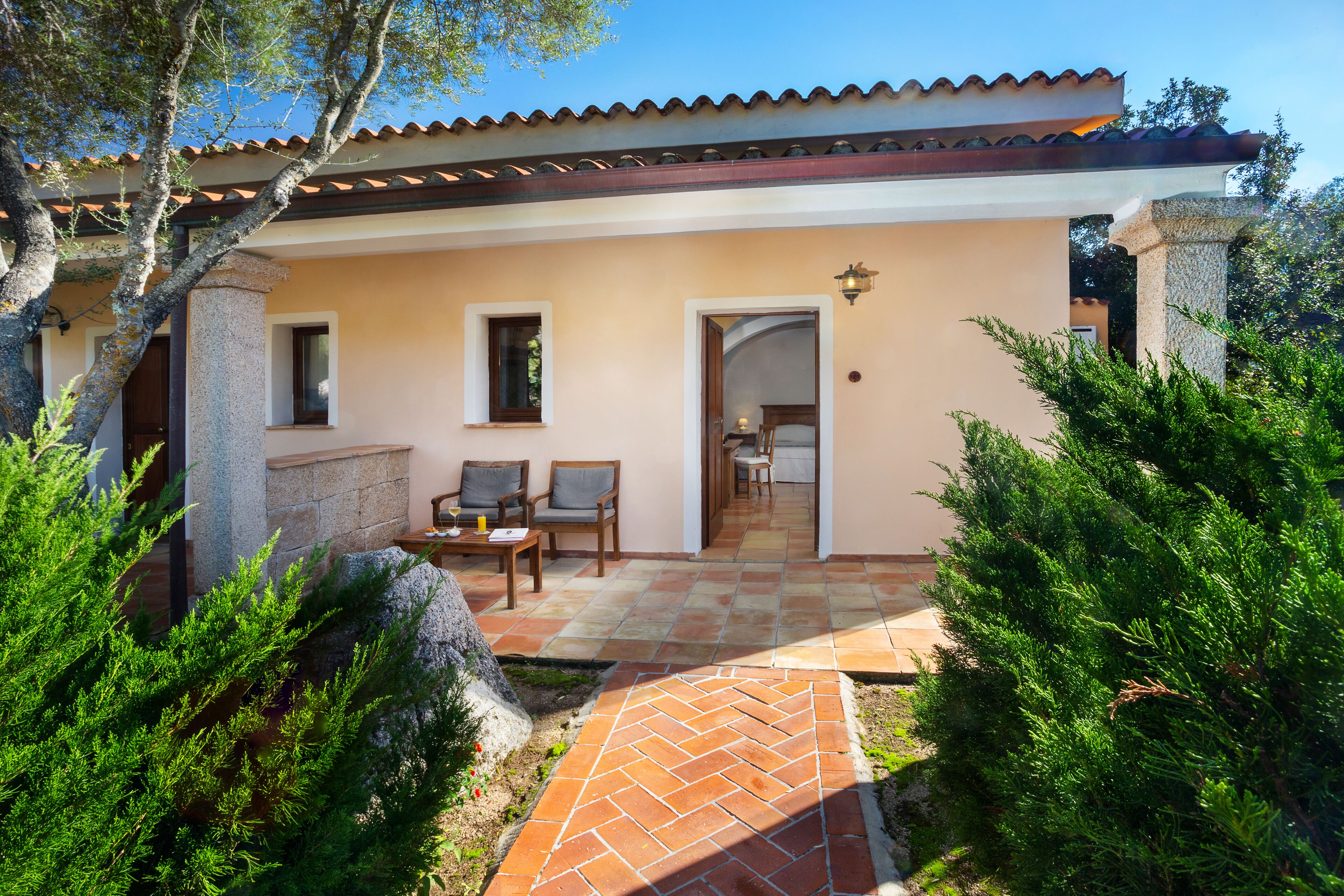 Une maison avec un patio carrelé, deux chaises et une table.
