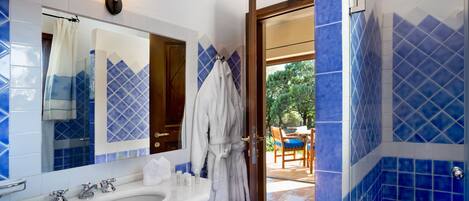 A bathroom with a large sink, a mirror, and a robe hanging on the door.