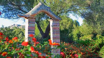 Un arco in legno con iscrizioni, circondato da un giardino fiorito di fiori rossi.