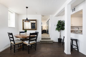 A dining area with a round table, chairs, a pendant light, and a potted plant. - The Kimball at Temple Square (Salt Lake City)