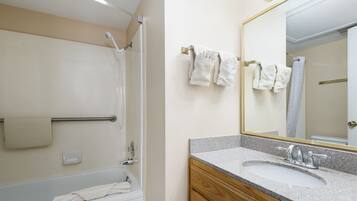 Une salle de bain avec une baignoire, un lavabo, un miroir et des serviettes suspendues à un porte-serviettes.