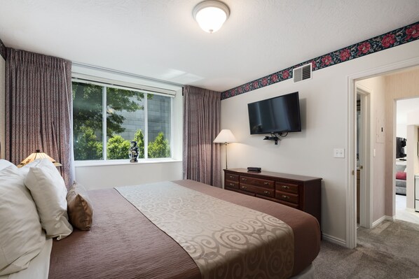 A hotel room with a large bed, a flat-screen TV mounted on the wall, a dresser, and a window with curtains. - The Kimball at Temple Square (Salt Lake City)