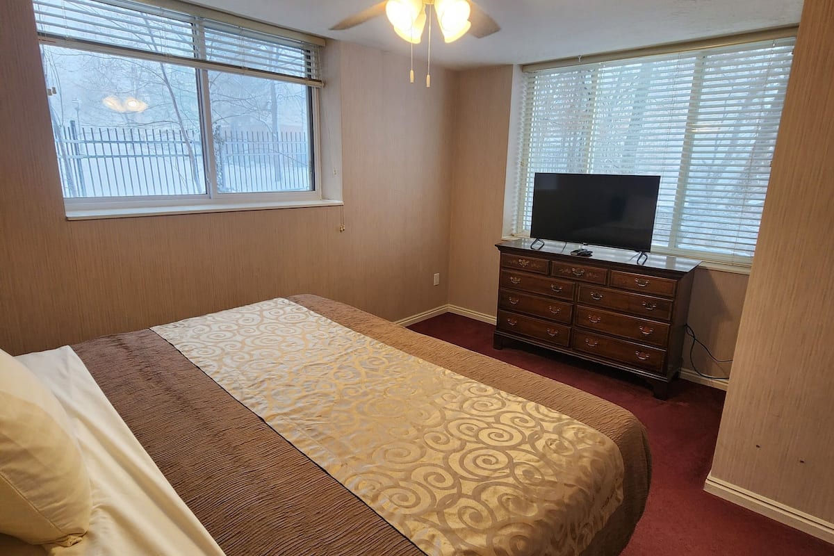 Ein Schlafzimmer mit einem Bett, einem Deckenventilator, einer Kommode und einem Fernseher.