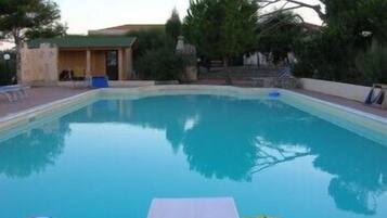 Relax by the pool surrounded by lush greenery and trees.