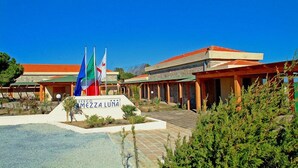 A hotel with a sign reading "BERGO MEZZA LUNA" and multiple flags. - Hotel Club Mezzaluna (Carloforte)
