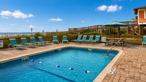A pool with lounge chairs, a wooden deck, and a view of the beach. - Ocean Forest Colony (Myrtle Beach)