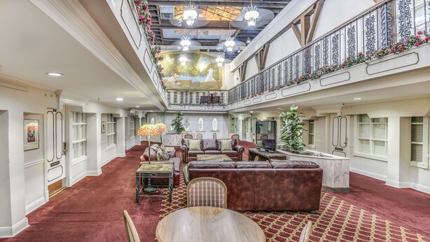 A spacious, elegantly decorated hotel lobby with a high ceiling, ornate railings, and a central seating area with a round table. - Plaza Suites Downtown New Orleans (New Orleans)