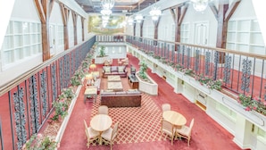 A spacious indoor area with a red carpet, wooden furniture, and decorative plants. - Plaza Suites Downtown New Orleans (New Orleans)