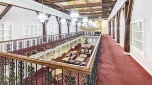 A spacious upper floor with a red carpet, wooden beams, and a balcony with ornate railings. - Plaza Suites Downtown New Orleans (New Orleans)