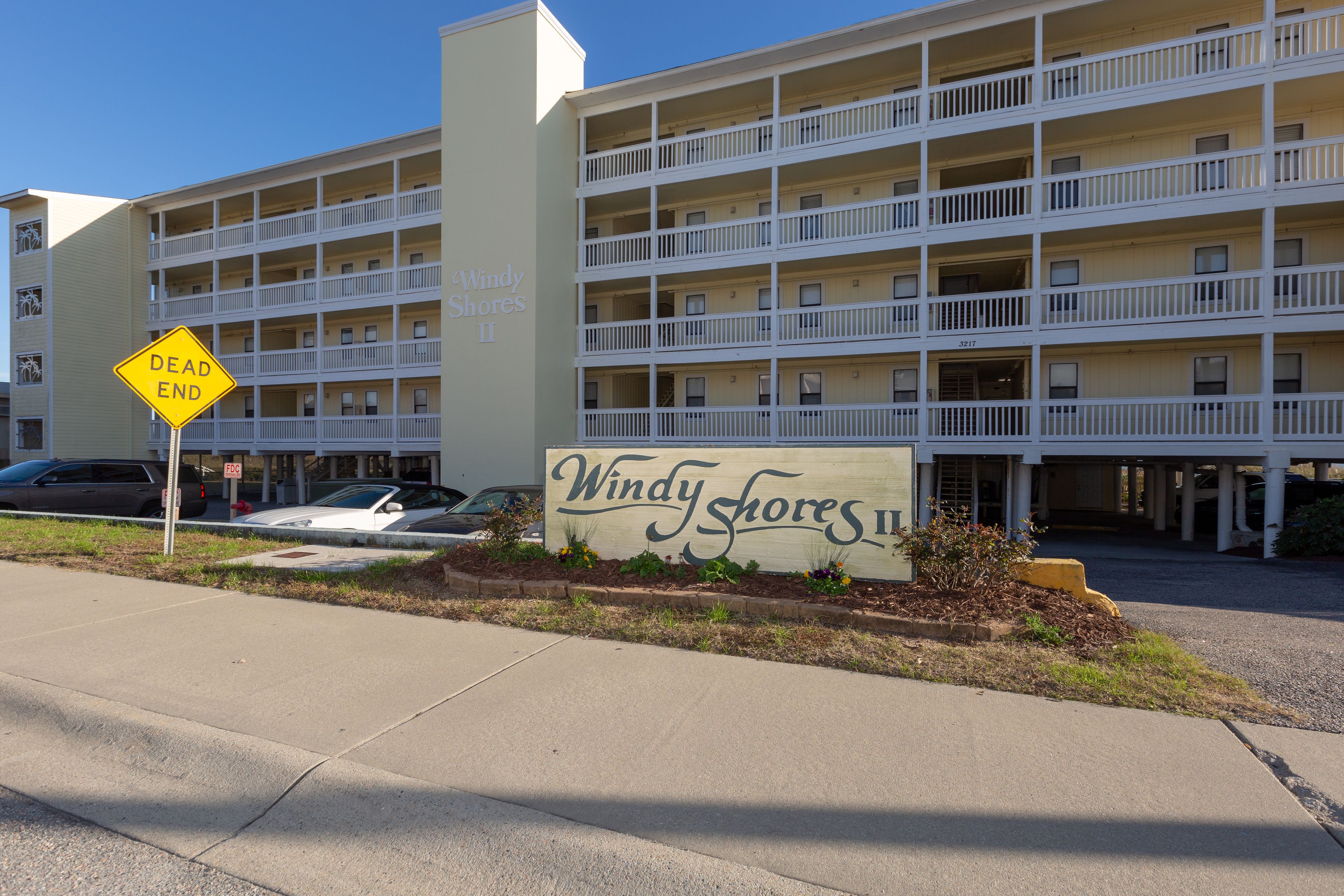 A multi-story hotel with balconies, a 'Dead End' sign, and a 'Windy Shores II' sign.