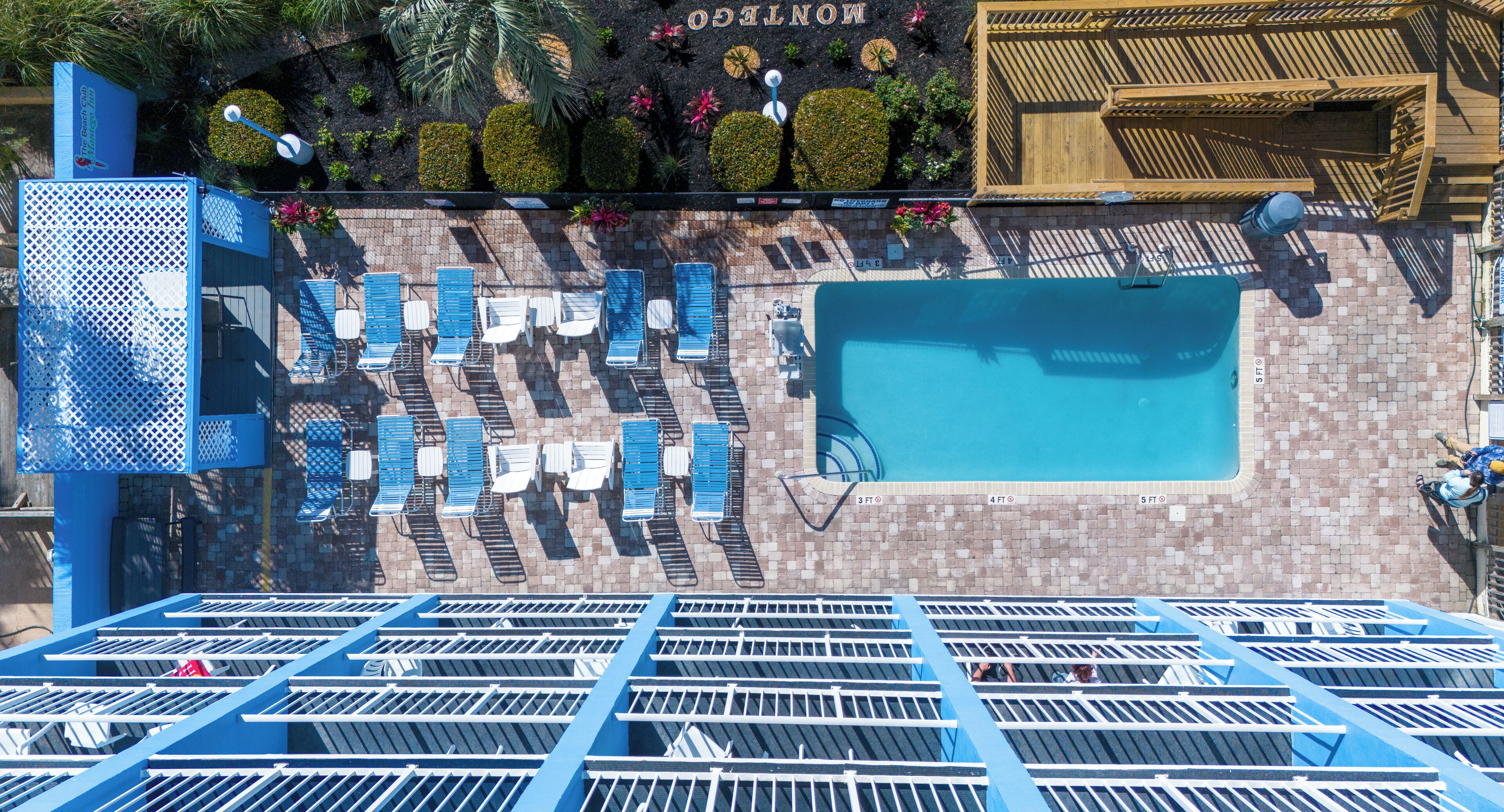 A rooftop pool area with blue sun loungers and a clear blue pool.