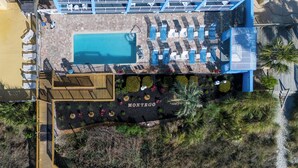 An aerial view of a resort with a swimming pool, sun loungers, and a boardwalk leading to a beach area. - Beach Club at Montego Inn (Myrtle Beach)