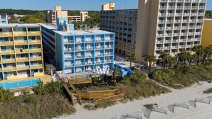A beachfront hotel with multiple balconies, a pool, and a beach area. - Beach Club at Montego Inn (Myrtle Beach)