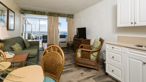 A compact living space with a sofa, dining table, wicker chairs, a kitchenette, and a view of the ocean. - Beach Club at Montego Inn (Myrtle Beach)