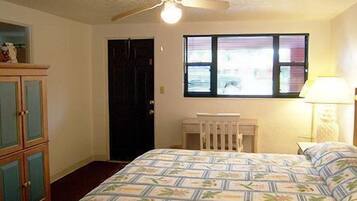 A bedroom with a bed, a window with blinds, a ceiling fan, and a dresser.