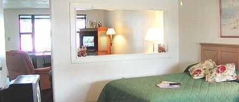 A bedroom with a bed, a mirror, a lamp, and a television.