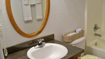 Un baño con un lavabo blanco, un espejo con marco de madera, un inodoro blanco y una bañera.