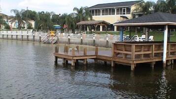 A waterfront property with a dock, lounge chairs, and a covered seating area.