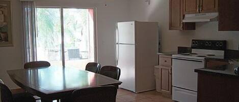 A kitchen with a dining area, white appliances, and a ceiling fan.