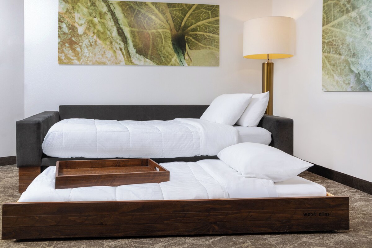 A modern bedroom with a bed, a bedside table, and a lamp.