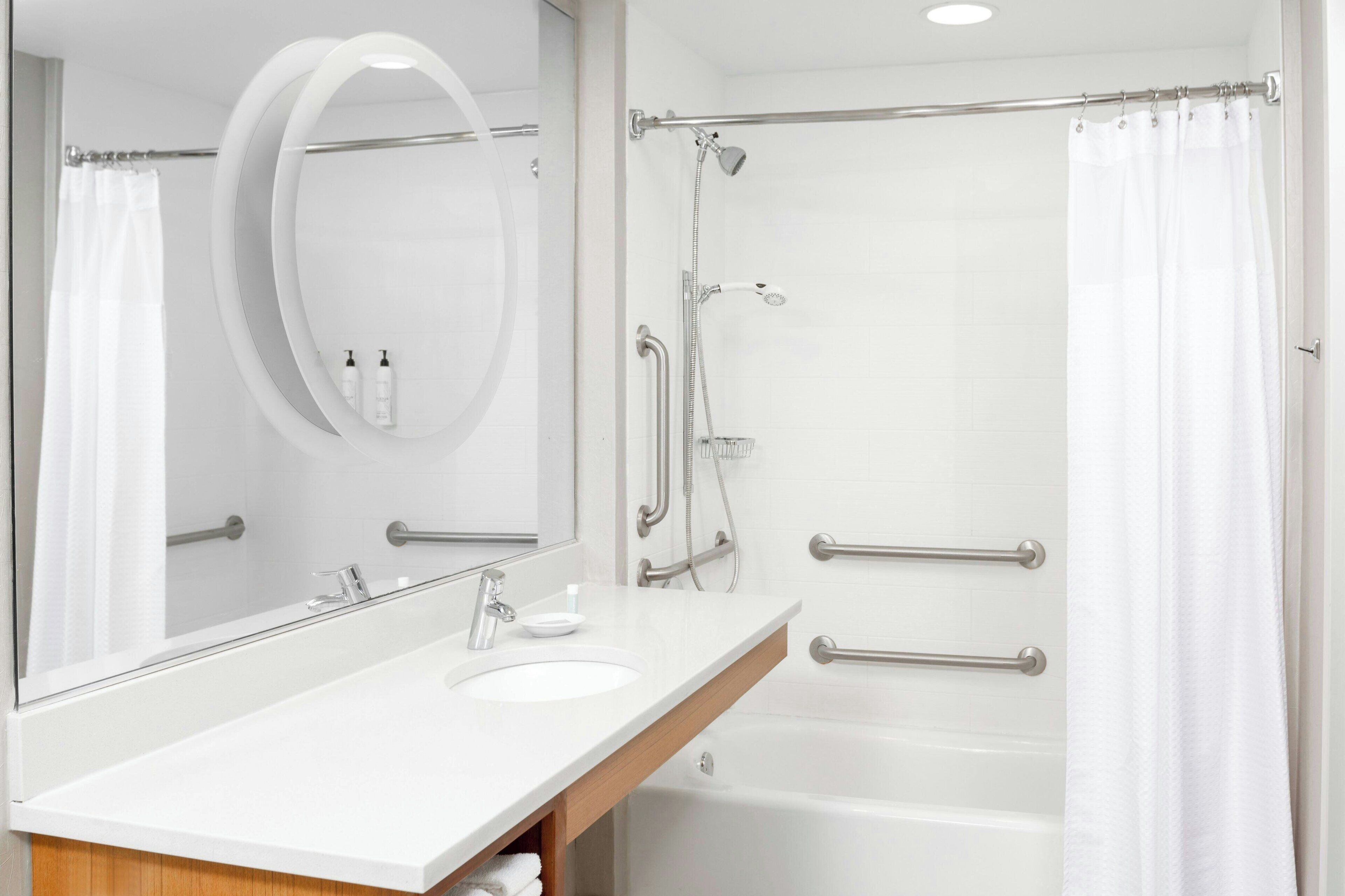 Un baño moderno con lavamanos blanco, espejo y zona de ducha.