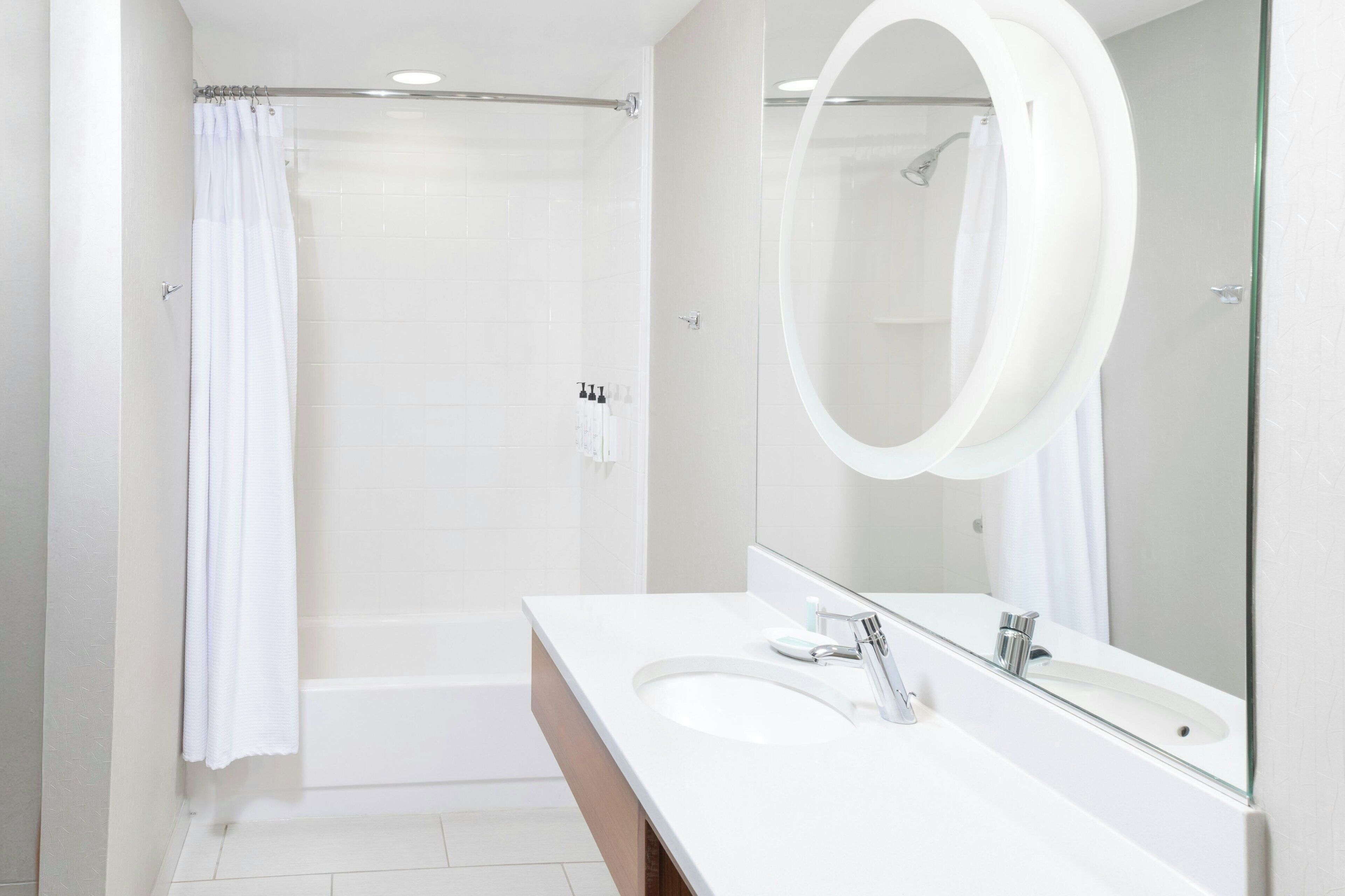 Une salle de bain moderne équipée d’une baignoire, d’une douche, d’un lavabo et d’un grand miroir.