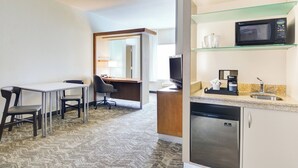 A hotel room with a kitchenette, a dining area with a table and chairs, a microwave, a coffee maker, and a refrigerator. - SpringHill Suites Shreveport-Bossier City/Louisiana Downs (Bossier City)
