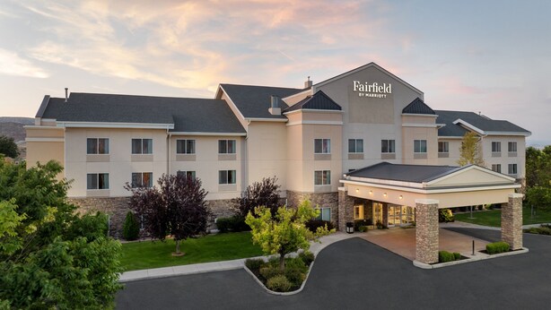 Un hotel grande de varios pisos con una entrada destacada y un camino de acceso arbolado.