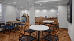 Un restaurante moderno con suelo de madera, mesas redondas y sillas azules.