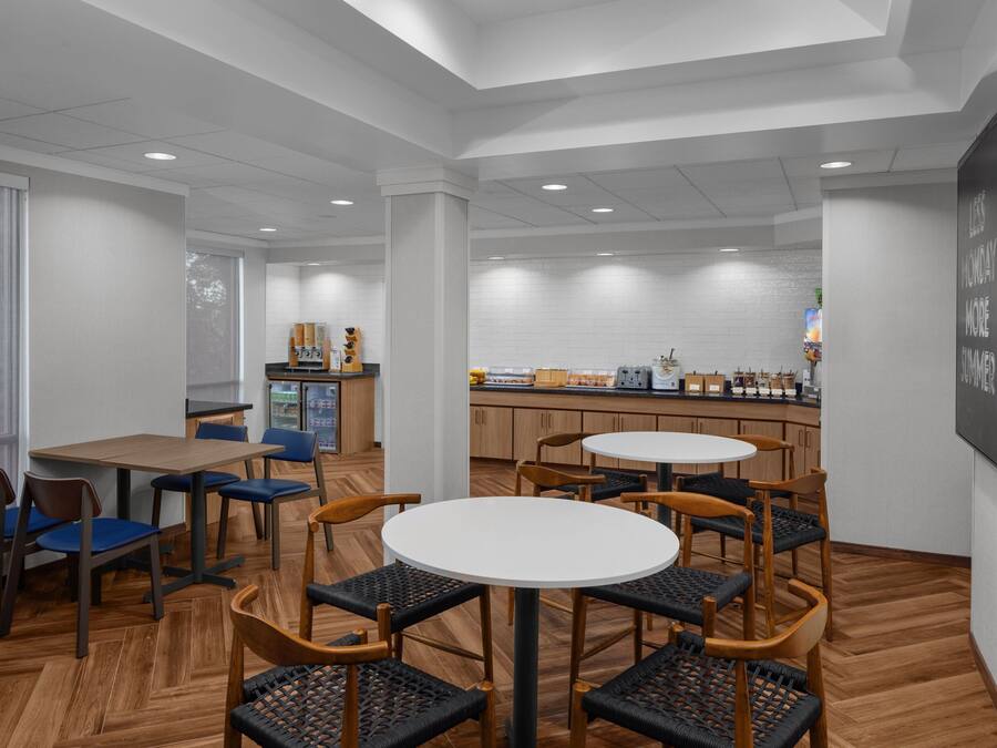 Un restaurante moderno con suelo de madera, mesas redondas y sillas azules.