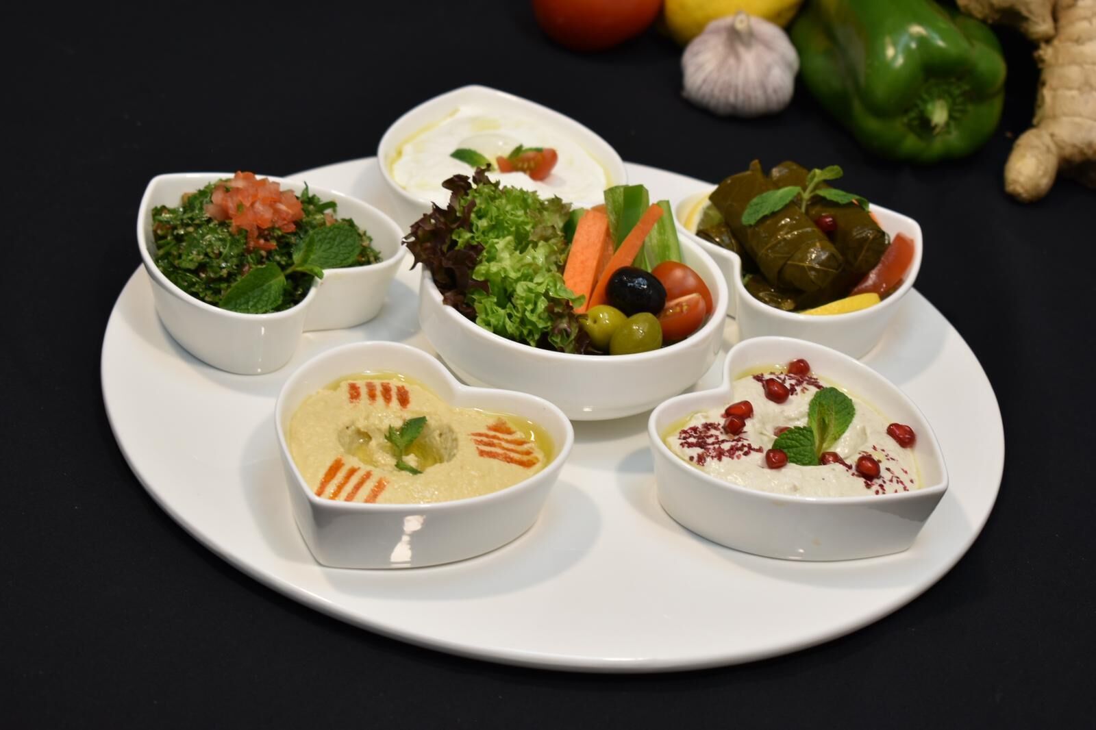 A white plate with six heart-shaped bowls containing various dishes.
