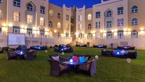 Un patio de hotel con mobiliario exterior y una pantalla grande.