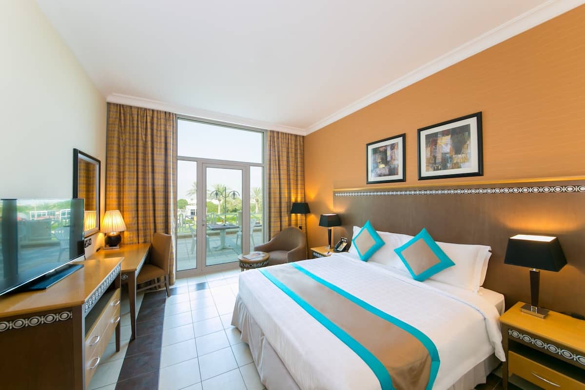 A hotel room with a bed, a TV, a desk, and a chair.