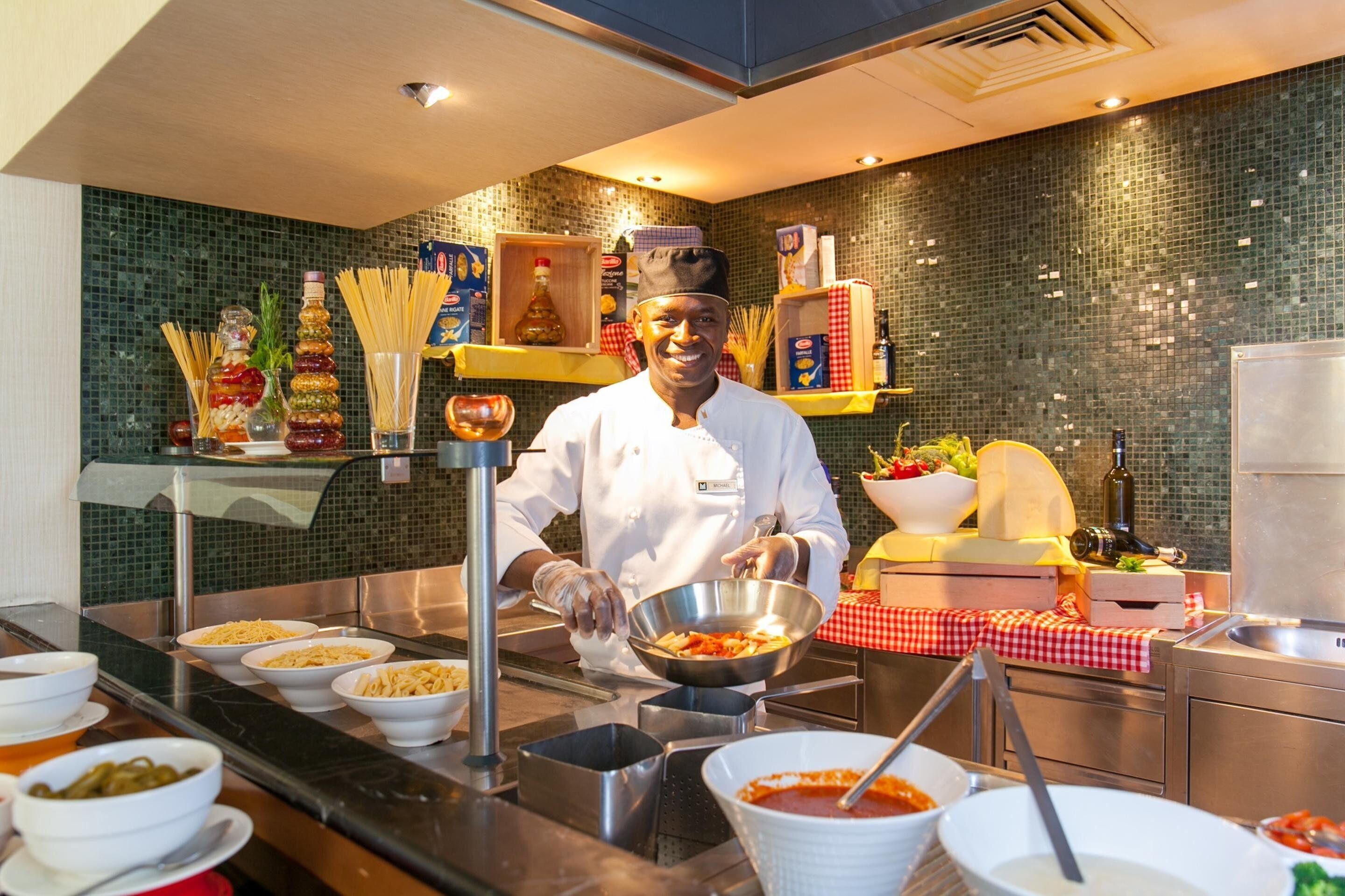 A chef preparing food in a kitchen with a tiled backsplash, various food items, and kitchen equipment.