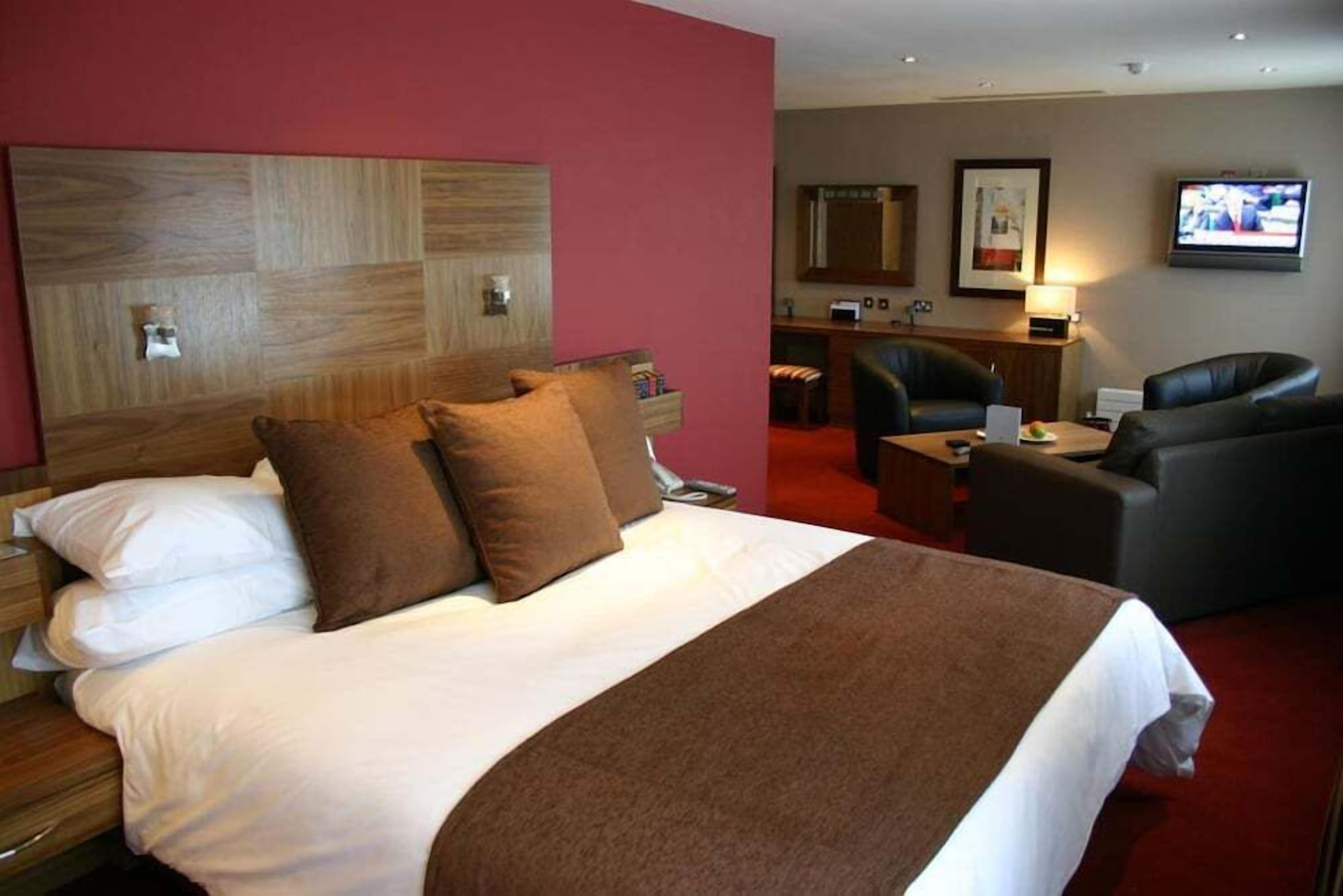 Een hotelkamer met een groot bed, een bureau, een stoel en een televisie.