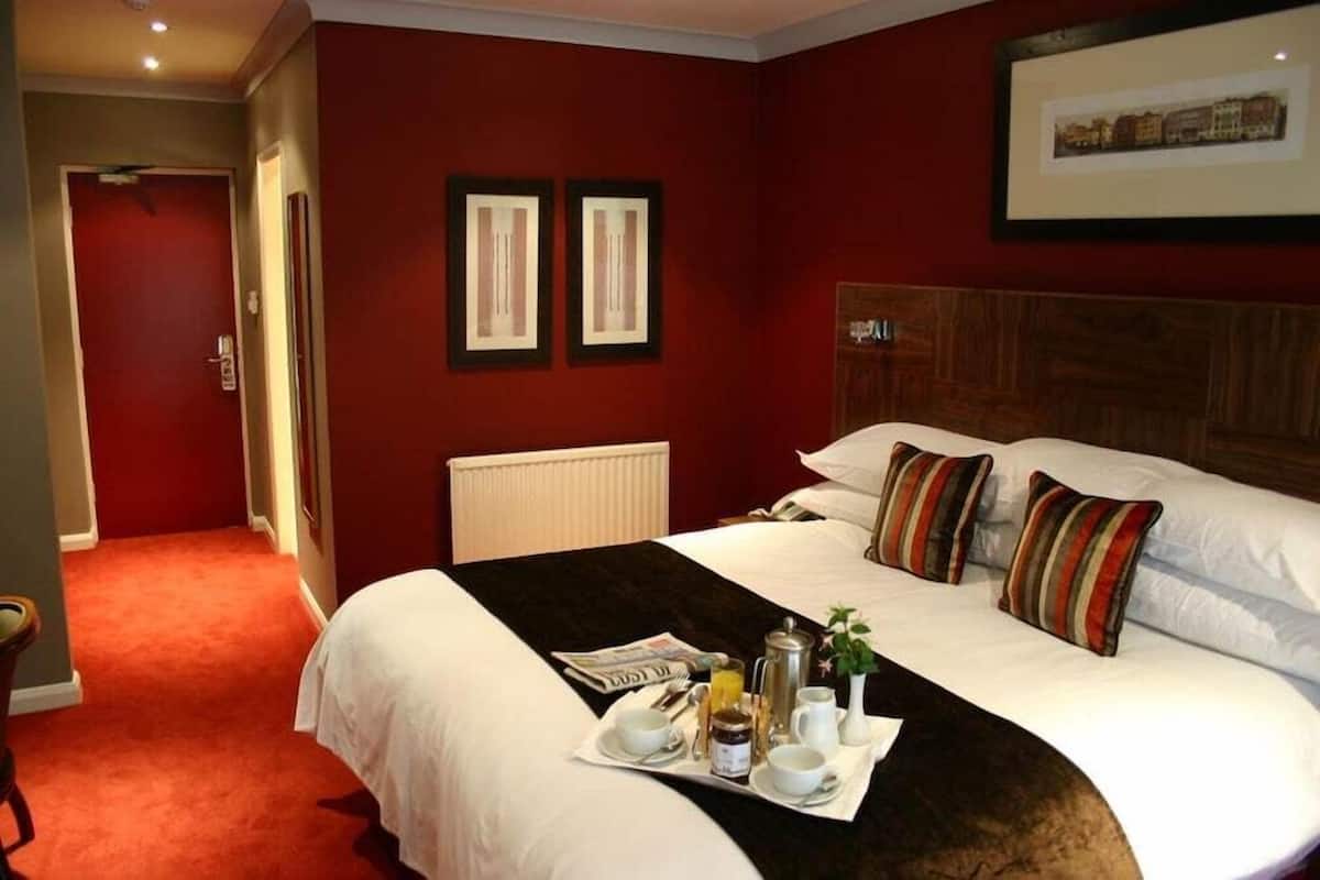 Een hotelkamer met een groot bed, een ontbijttafel en twee ingelijste foto's aan de muur.