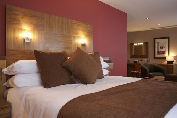 A hotel room with a large bed, two wall-mounted lights, a wooden headboard, a desk, and a chair. - Beamish Park Hotel (Newcastle-upon-Tyne)
