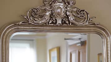 A mirror with an ornate silver frame and a decorative top.