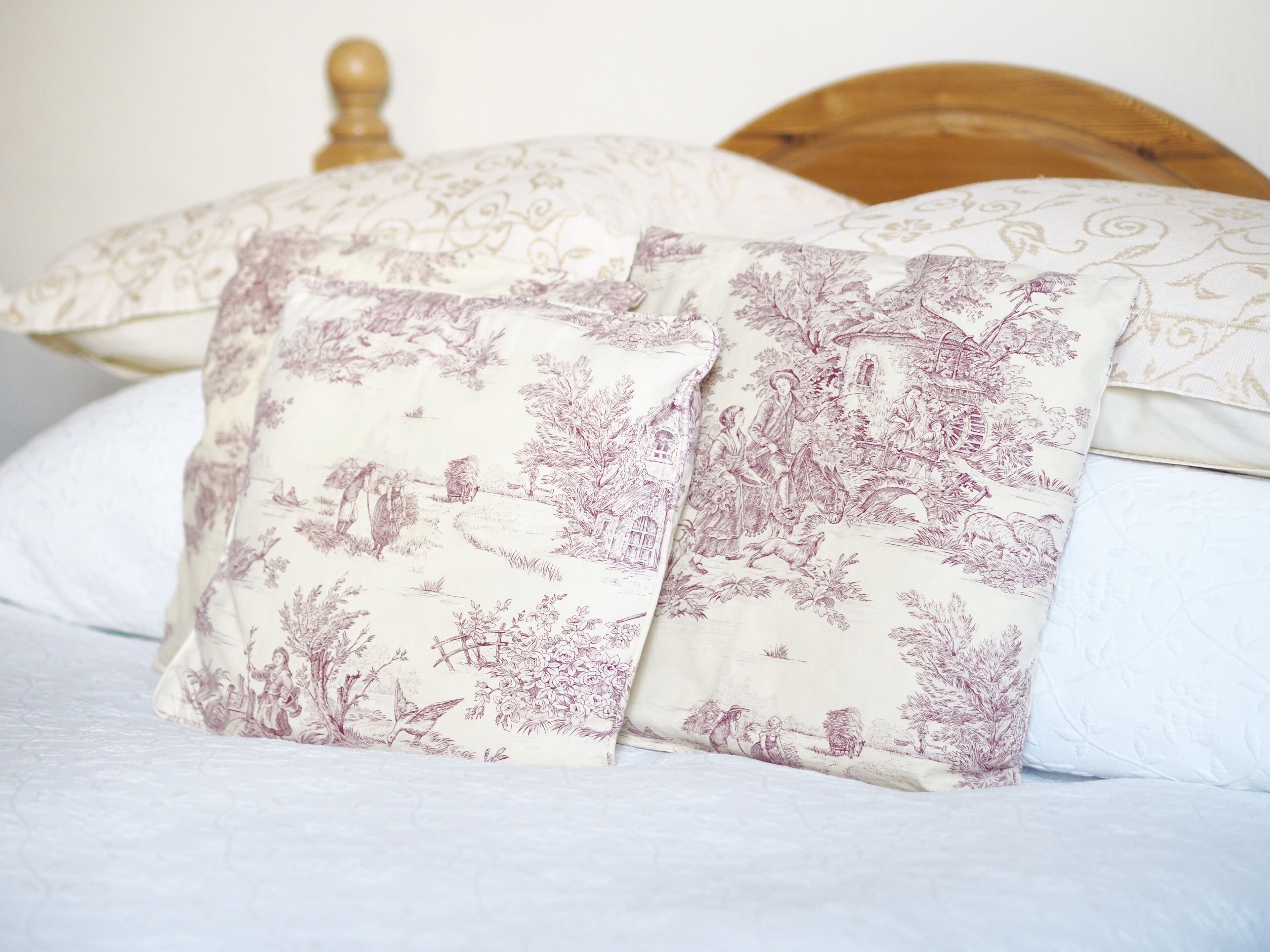 A bed with floral-patterned pillows and a wooden headboard.