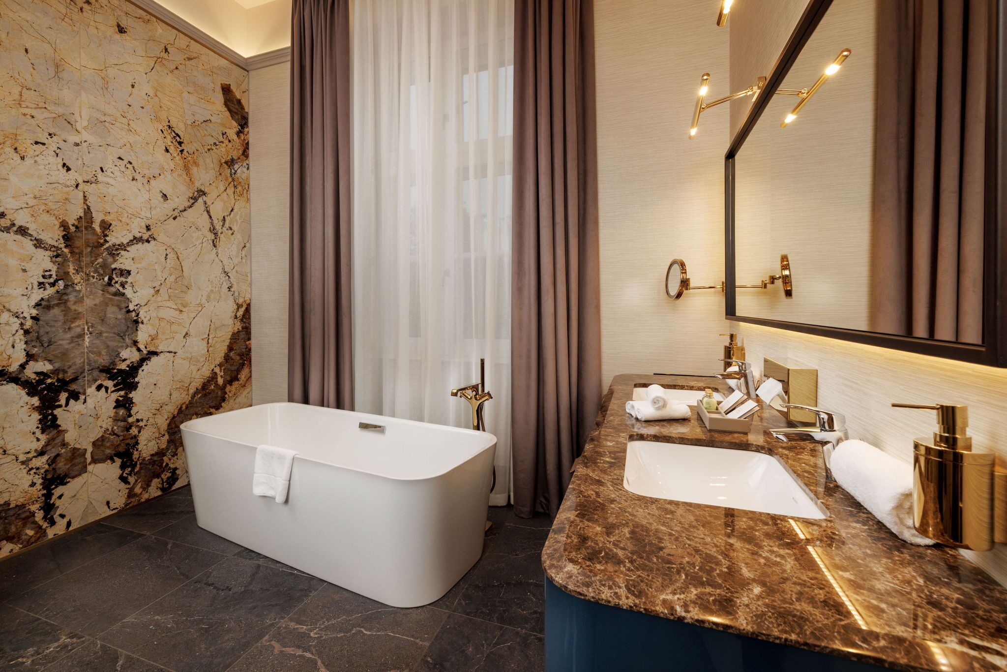 A modern bathroom with a freestanding bathtub, a marble countertop sink, and a large mirror.