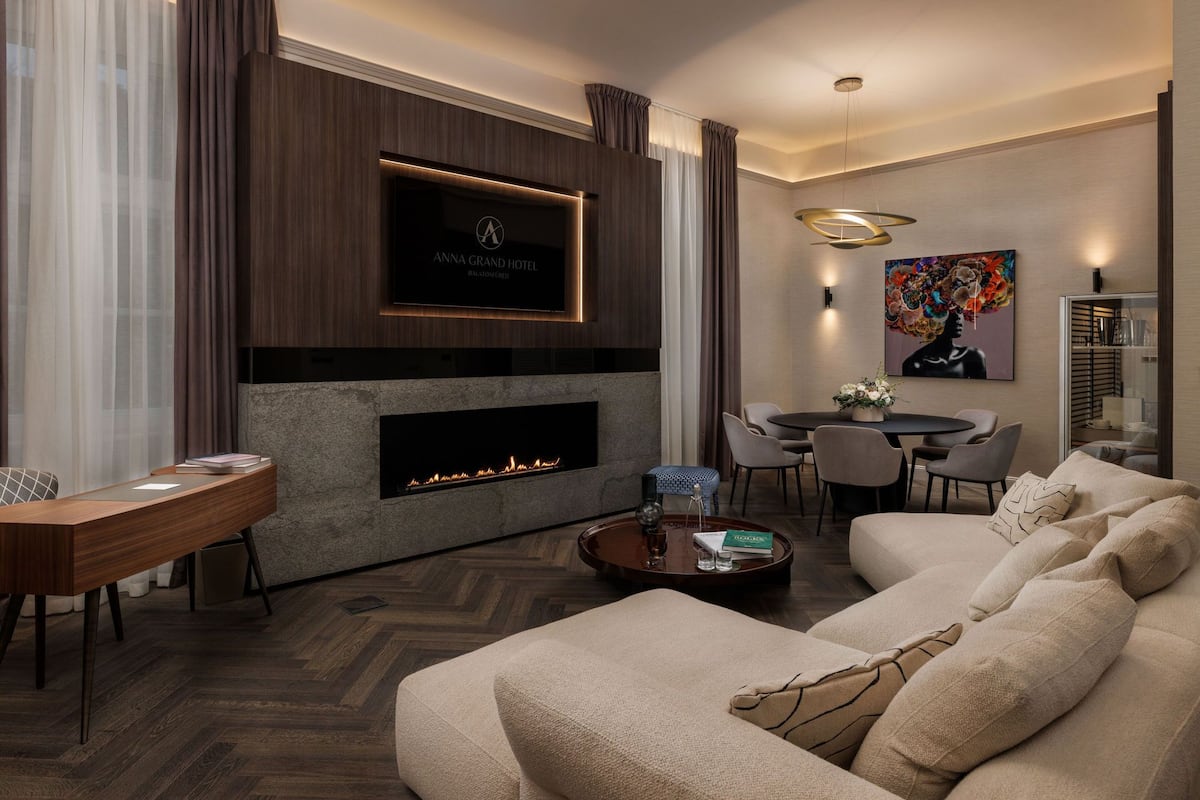 A modern living room with a fireplace, a flat-screen TV, a dining area, and a sofa.