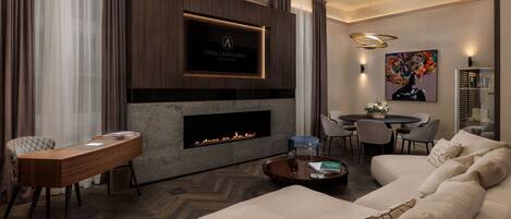 A modern living room with a fireplace, a flat-screen TV, a dining area, and a sofa.